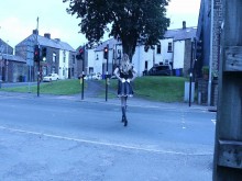 Crossdressed en uniforme de mucama en una calle con autos que pasan