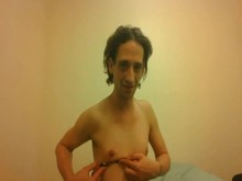 Chica trans en topless tratando de sostener un bolígrafo con sus pequeñas tetas